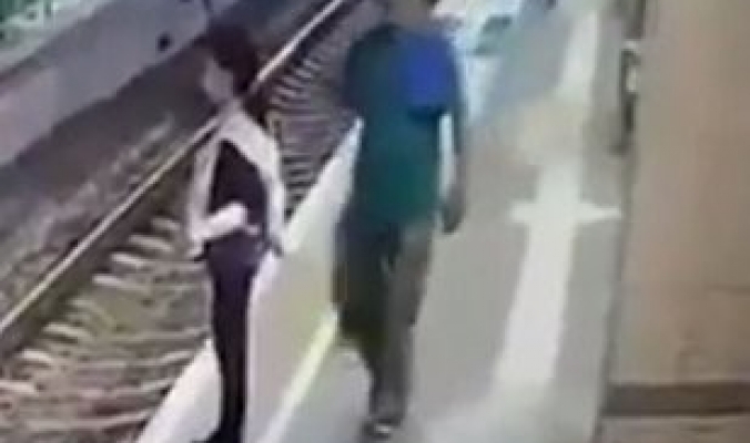 بالفيديو...رجل يدفع فتاة على قضبان قطار بدم بارد وبنذالة مطلقة